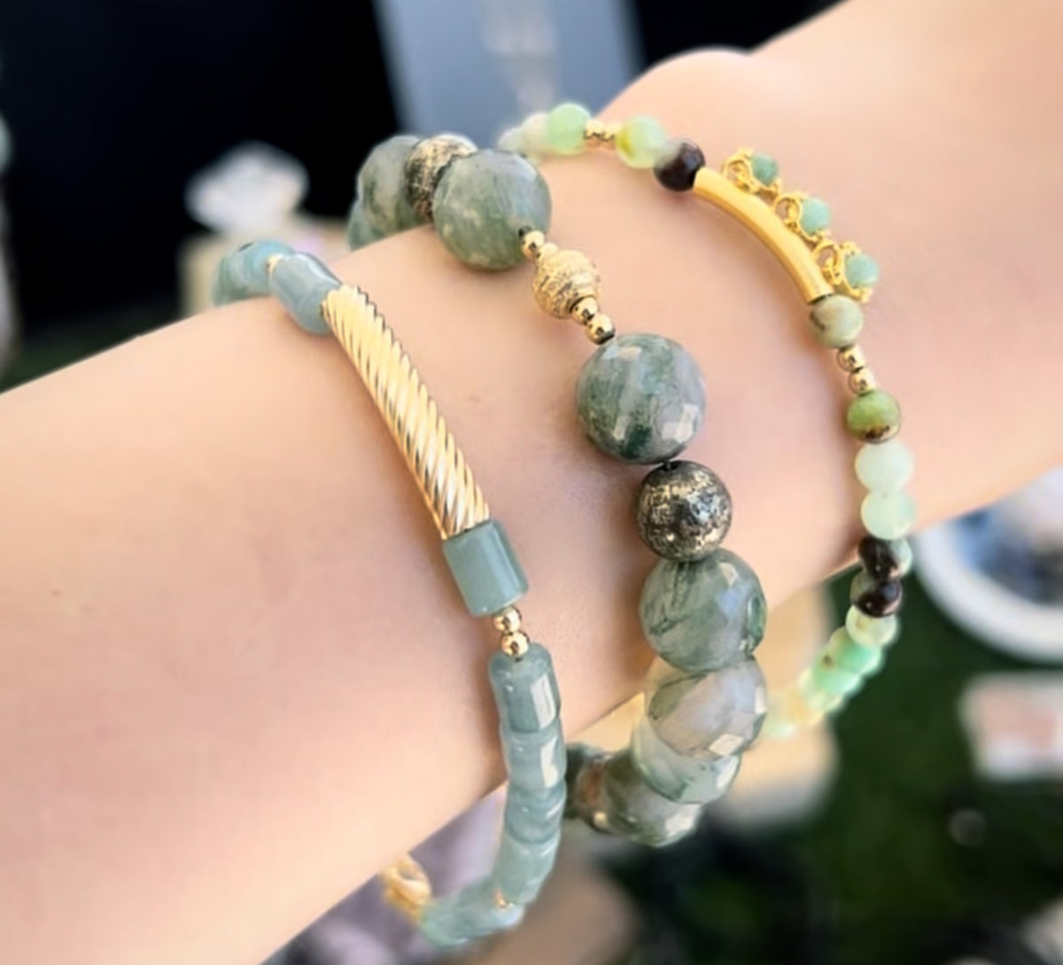 Close-up of a wrist wearing three beaded bracelets with gold accents.