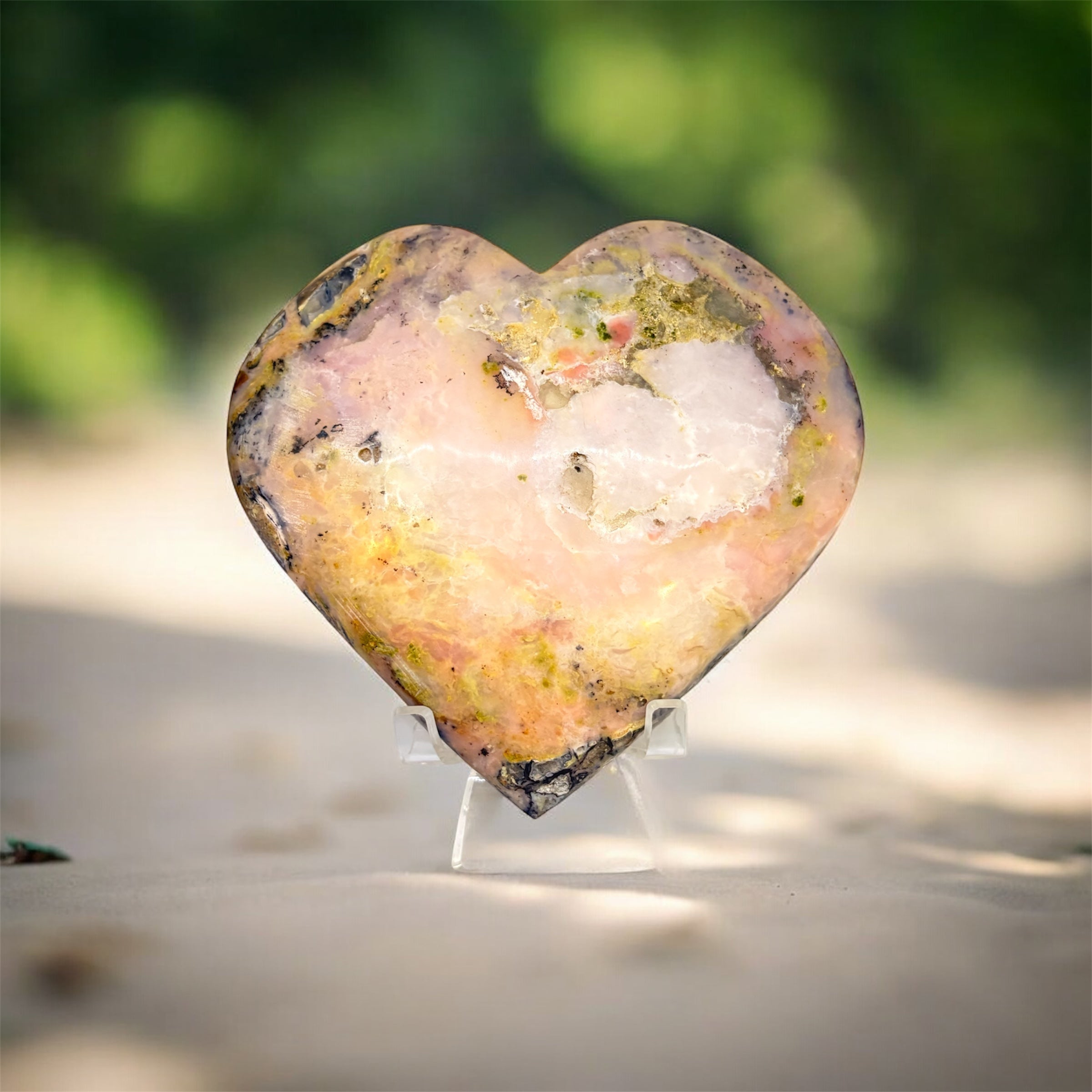 Heart-shaped crystal on a stand with a blurred natural background